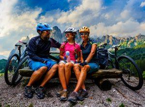 Cycling family outdoor adventure in Dolomites mountains landscape. Father, mother and daughter cycling MTB enduro trail.