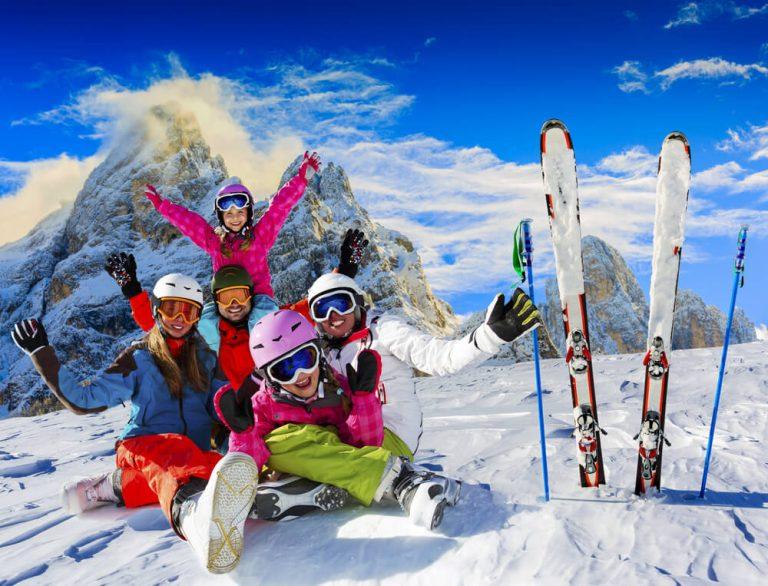 Skiing family enjoying winter vacation on snow in sunny cold day in mountains and fun. San Martino di Castrozza, Italy.